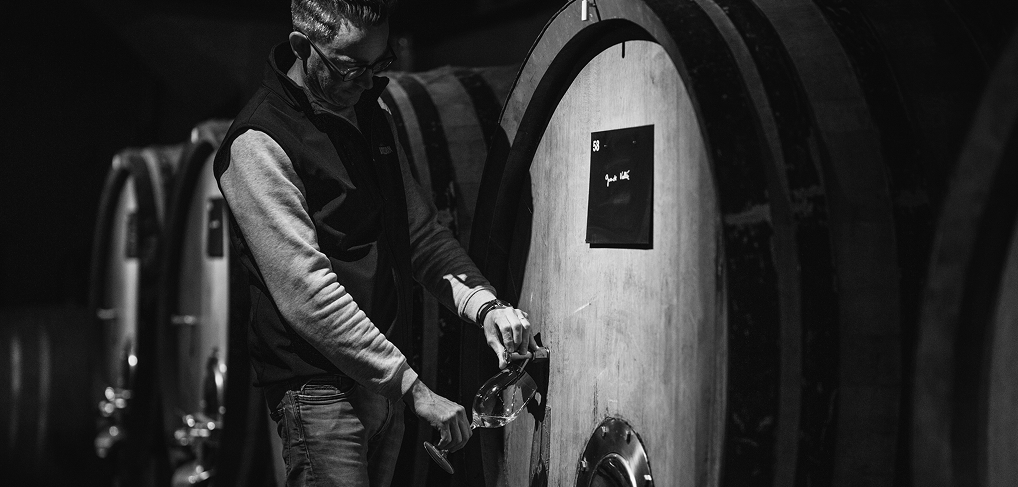 Employé vérifiant le vin dans une cuve de bois au sein de la cave de Champagne Jacquesson